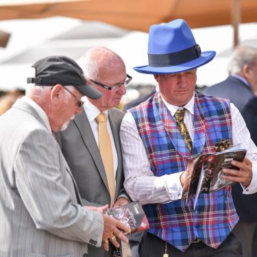 A man in a very jaunty hat studying the racecard