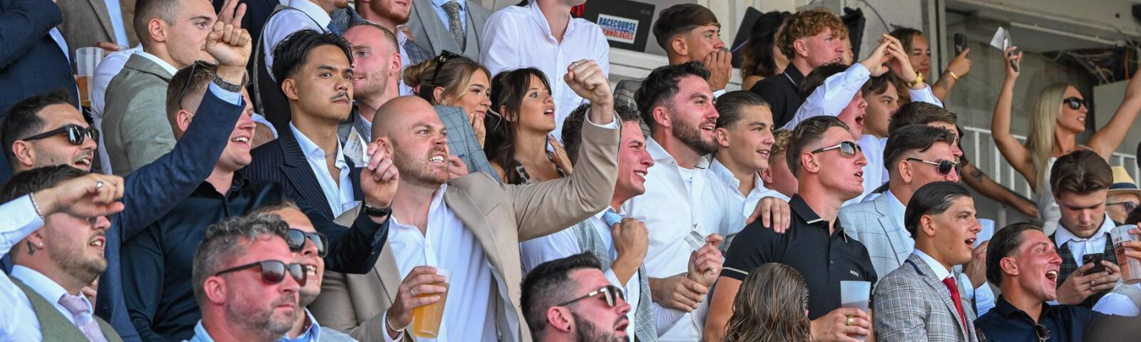 A large group of guys watching the races from the grandstands at Southwell Races