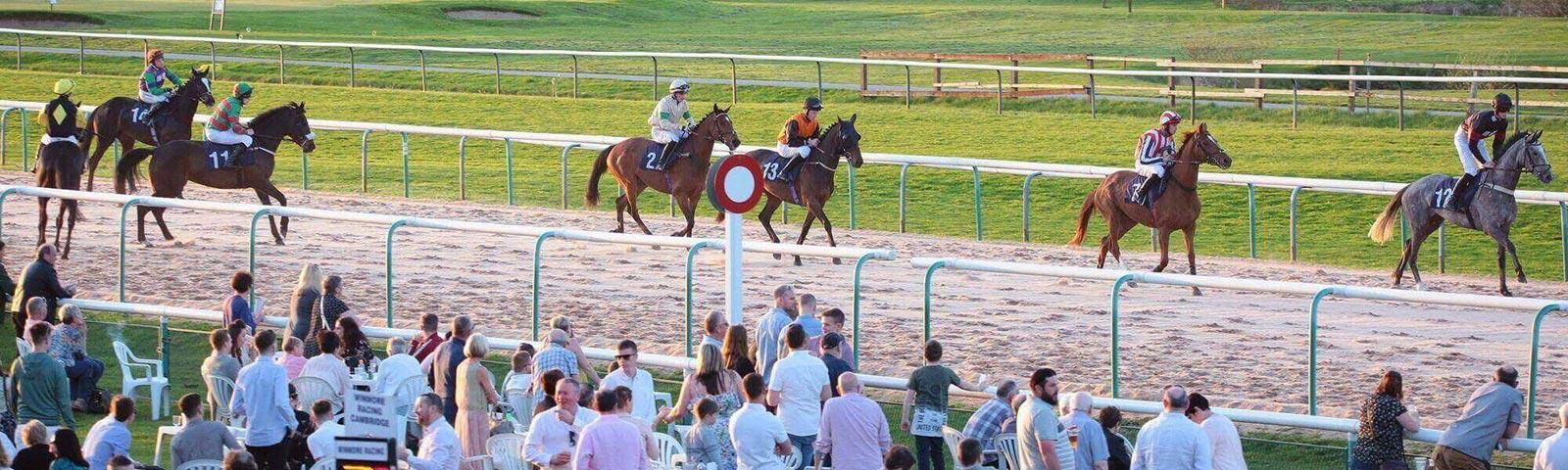 Horses trotting passed the finishing post at Southwell Racecourse