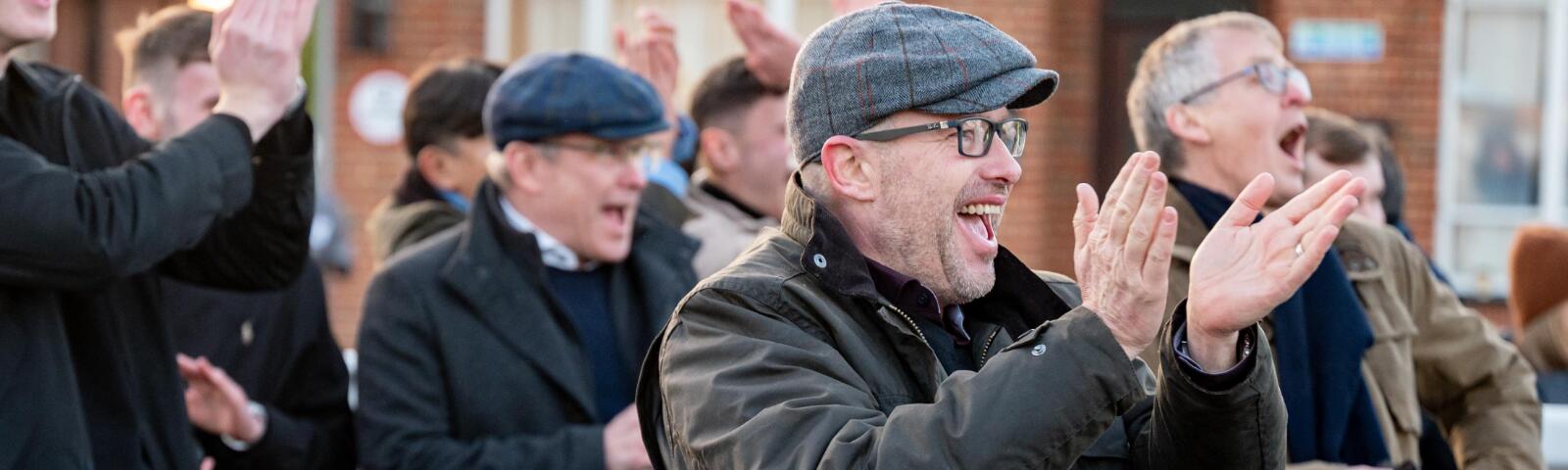 A group of race goers cheering the result of a race.